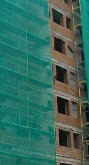 Multi-storey building under construction wrapped in green shade net