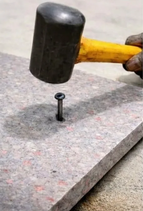 Hammer driving a nail into a recycled plastic shuttering sheet